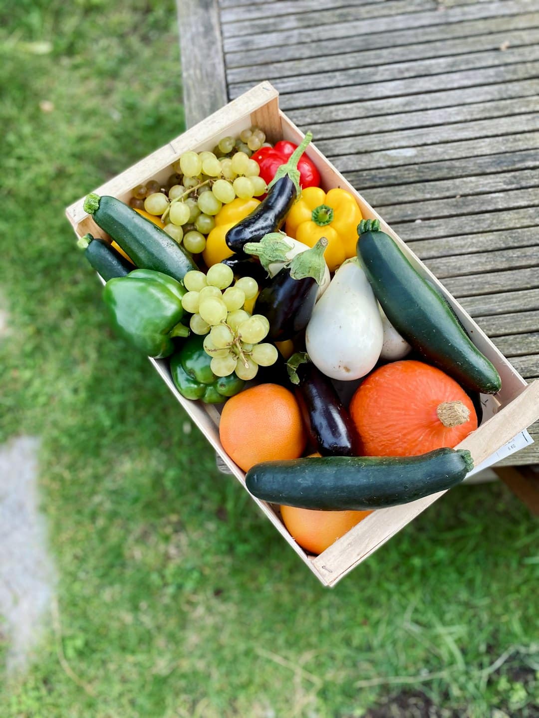 Cassa di legno traboccante di frutta e verdura colorata su un tavolo da picnic.